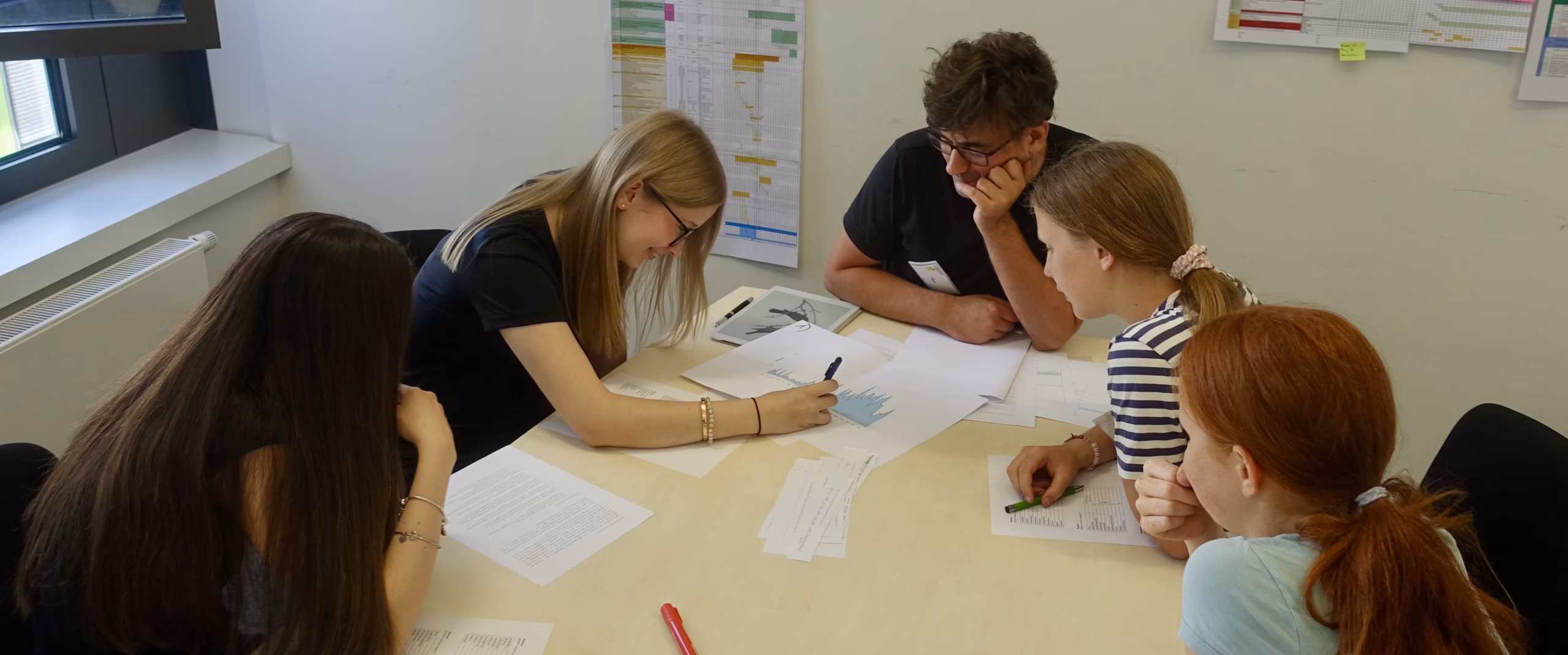 Jugendliche sitzen im Rahmen eines Projekttages um einen Tisch und lösen Aufaben.