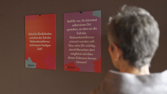 Eine Person blickt auf ausgestellte Plakate des "Memo-Projektes".