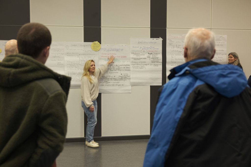 Workshop, bei dem eine Person etwas auf Plakaten zeigt.