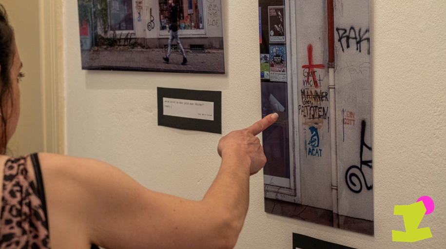 Eine Person zeigt auf ein Bild an der Wand zum Thema "Street Art" und Konflikt.