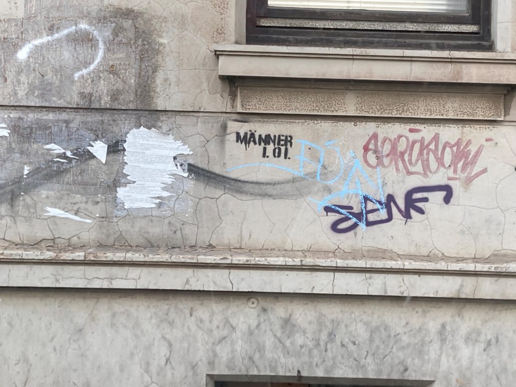An einer Wand steht "Männer lol".