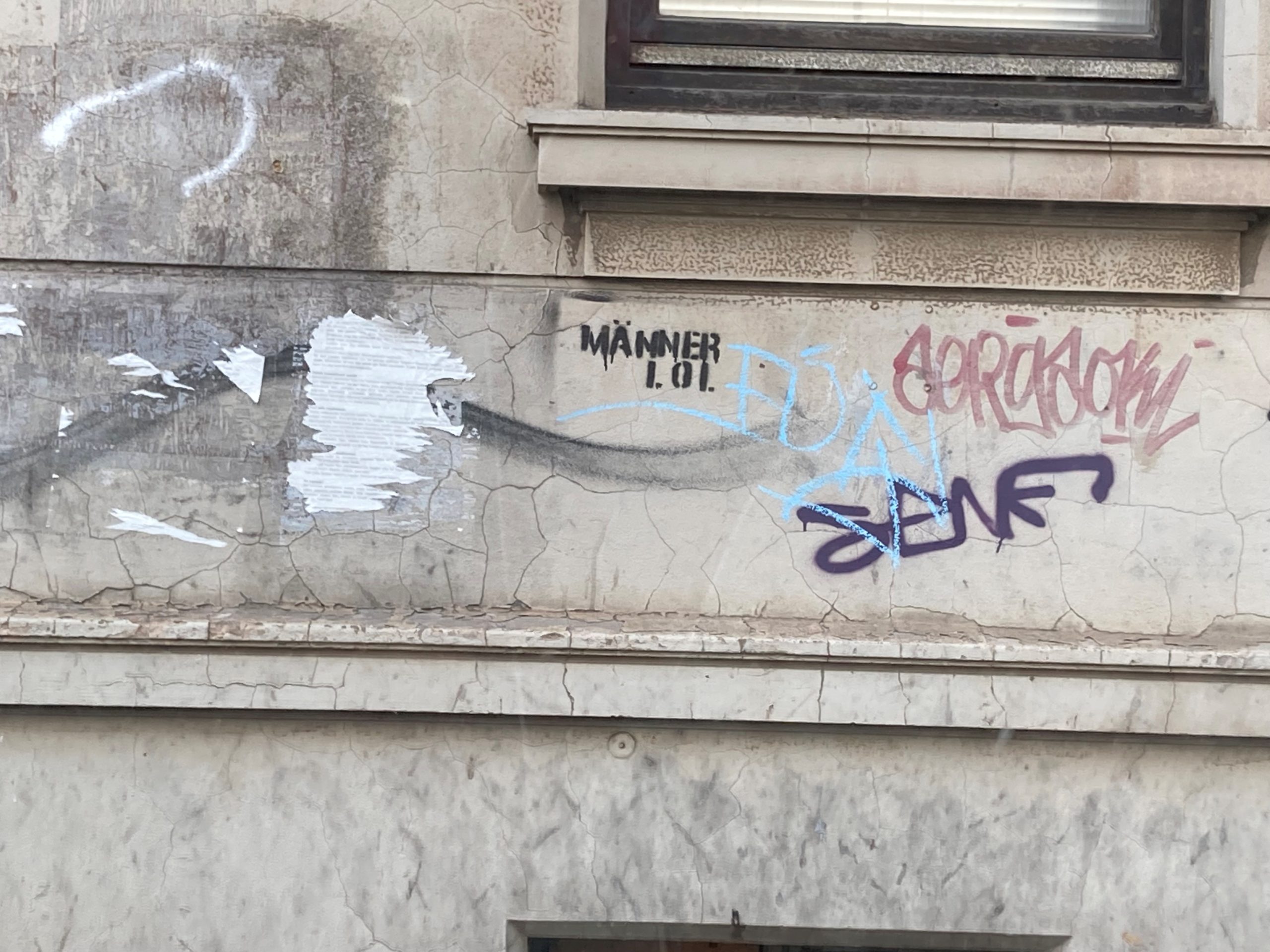 An einer Wand steht "Männer lol".